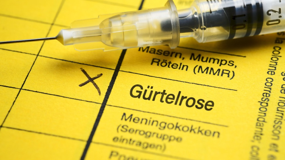 Impfpass mit Eintrag zur Gürtelrose-Impfung und Spritze